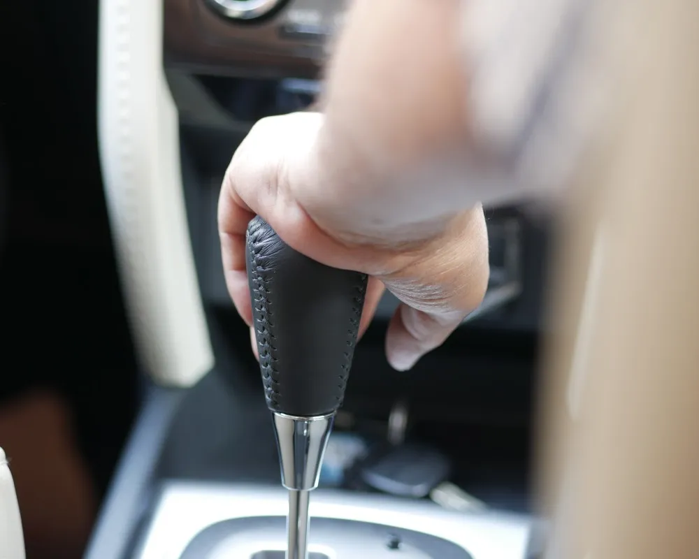 Close-up of a car's interior highlighting the gear lever, an essential part of the transmission system that allows the driver to shift gears manually or automatically.