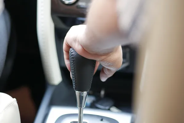 Primer plano del interior de un coche en el que se ve la palanca de cambios, parte esencial del sistema de transmisión que permite al conductor cambiar de marcha manual o automáticamente.