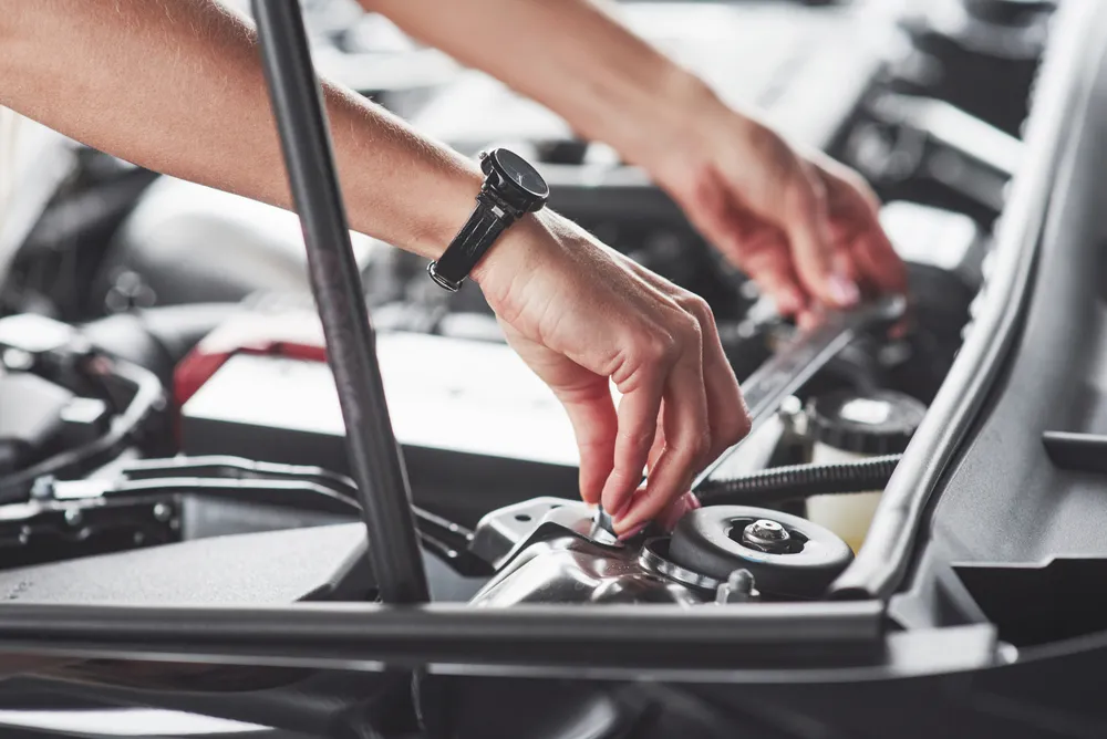 Detailed close-up of a mechanic’s hands performing hands-on adjustments and inspections on engine components during professional tune ups