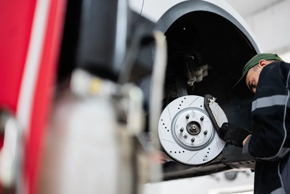 Experienced mechanic carefully removing brake components from a vehicle as part of comprehensive brake service and repair to maintain safety and efficiency