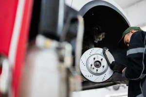 Mecánico experimentado que retira cuidadosamente los componentes de freno de un vehículo como parte del servicio integral de frenos y reparaciones para mantener la seguridad y eficiencia