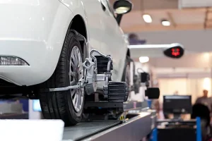 Wheel Alignment Service On White Car Showing Alignment Device Installed On Front Tire For Precision Adjustment And Safety