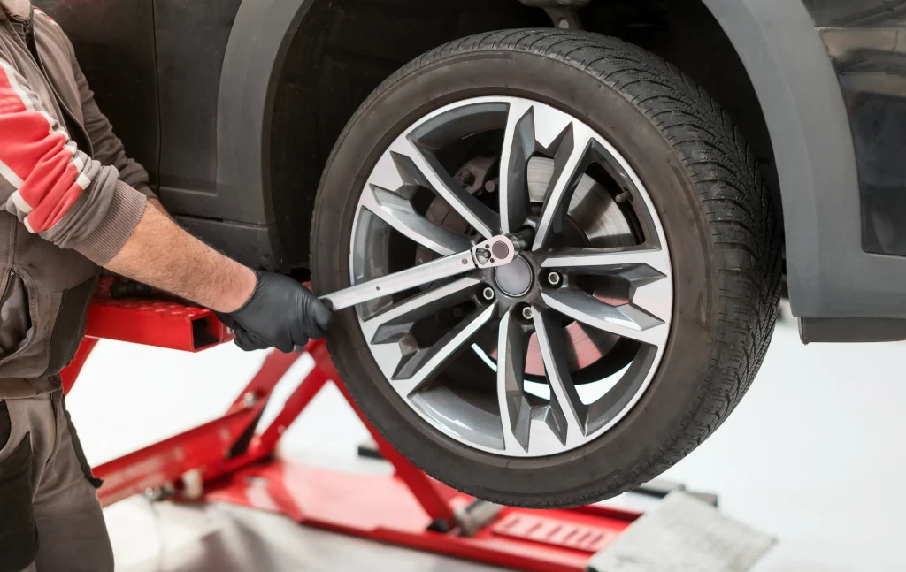 An auto mechanic using a torque wrench to tighten the lug nuts on a wheel during a tire rotation, ensuring proper fit and safety.