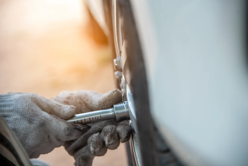 A close-up view of a person's hands, possibly a mechanic or a car owner, diligently performing a tire repair on a flat or damaged car tire, likely patching a puncture or checking the valve.