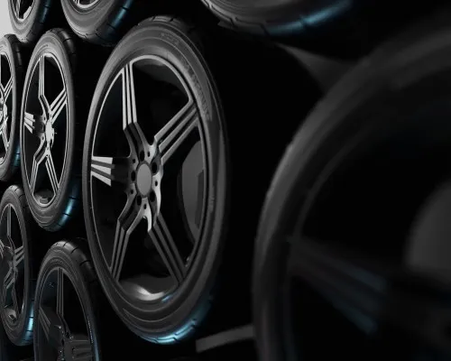 Varias de las mejores llantas para carros apiladas en un almacén o exhibición oscura, mostrando su diseño de rin plateado.