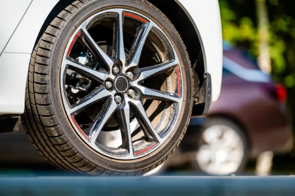 Rueda de coche en primer plano, mostrando las mejores llantas para carros con banda de rodadura y un rin de aleación multirradio.
