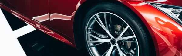 Panoramic close-up of one of the best tires for cars mounted on a modern alloy wheel of a red car.
