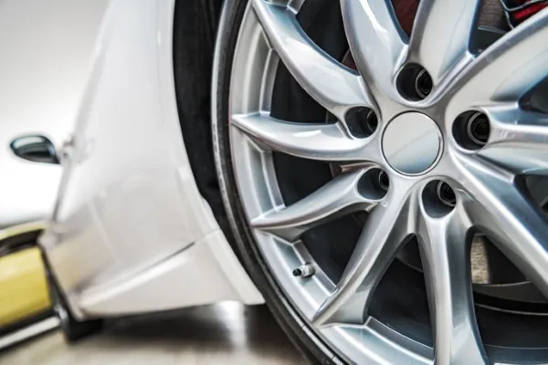 Extreme close-up of a matte silver alloy rim paired with one of the best tires for cars on a showroom vehicle.