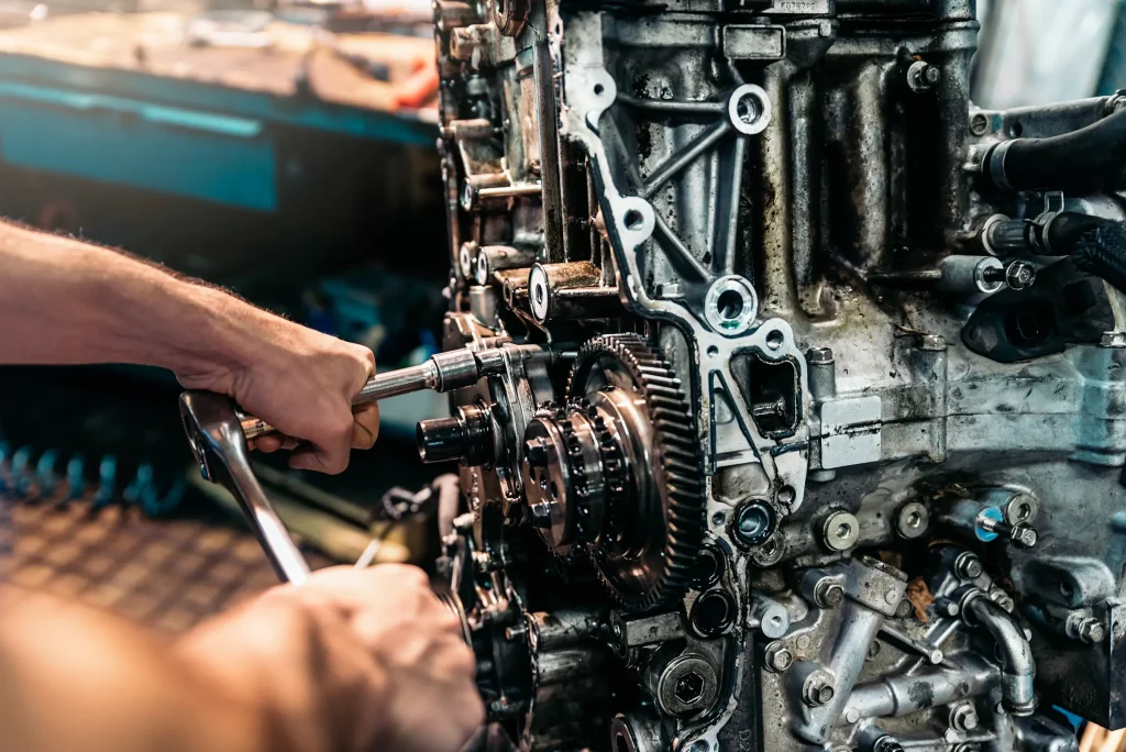 Técnico automotriz ajustando pernos durante la reparación de transmisión estándar de un bloque de motor robusto.