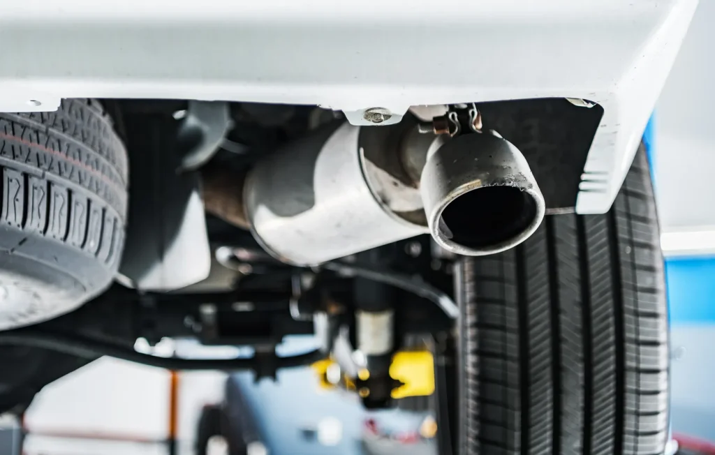 Muffler and tailpipe on a car lifted onto a lift, ready for muffler repair at the shop.