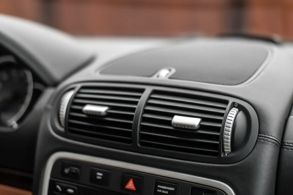 Close-up of the central air conditioning vents and dashboard of a luxury vehicle, after professional air conditioning service.