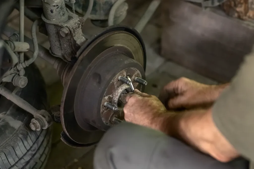 Mechanic’s hands using a wrench to repair a car's brake system during a brake service.