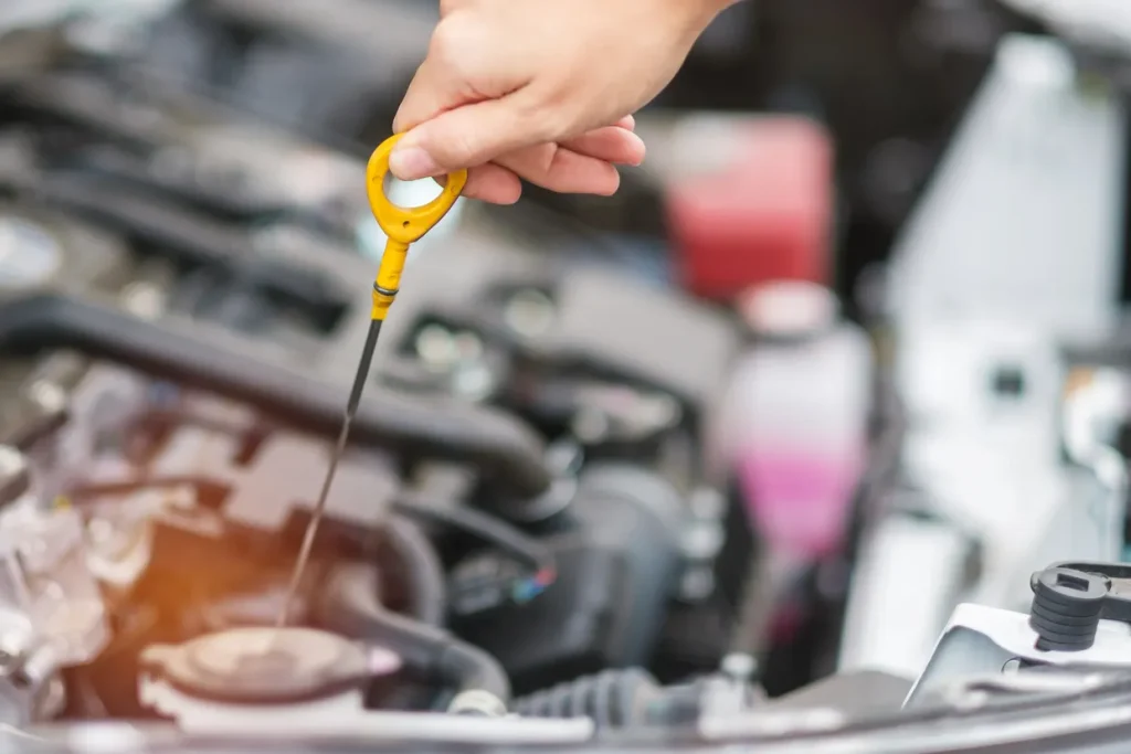 Close-up of a hand pulling out the oil dipstick to check a vehicle's oil level and prepare for an oil change.