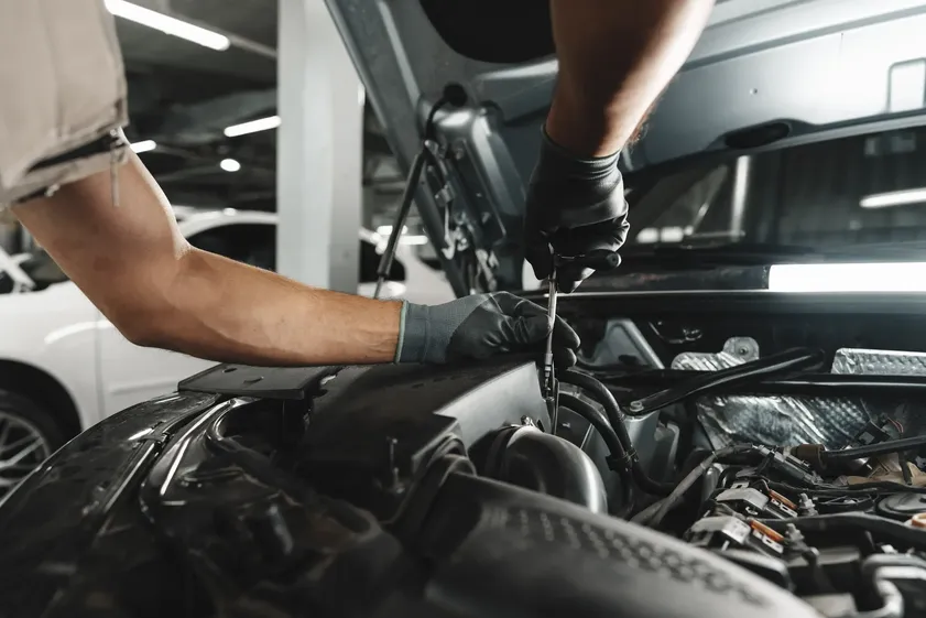 A mechanic using a socket wrench to tighten bolts on a car's engine component as part of a detailed "car maintenance" routine.