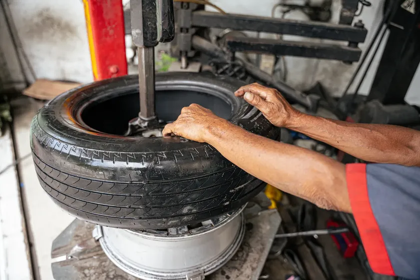 Mecánico operando una máquina desmontadora para quitar un neumático de un rin, en un taller de tire repair.