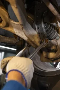 Mecánico realizando una revisión de la suspensión y los neumáticos durante un servicio de reparación de automóviles.