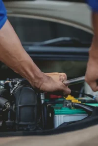 Close-up of a mechanic’s hands using a wrench to adjust engine components as part of professional tune ups for optimal vehicle performance