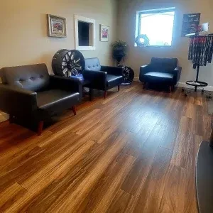 Interior view of a modern automotive shop lobby featuring stylish black armchairs and decorative custom wheels